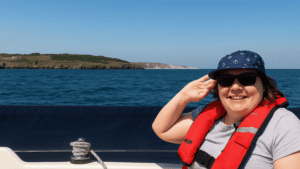 Smiling person sailing near a scenic coastline