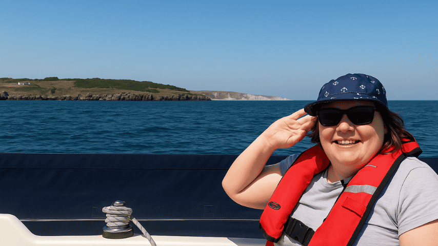 Smiling person sailing near a scenic coastline