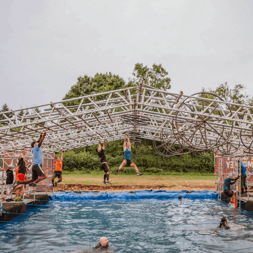 People tackling outdoor obstacle course over water