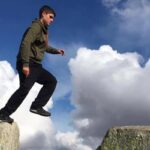 Person jumping across two large rocks outdoors