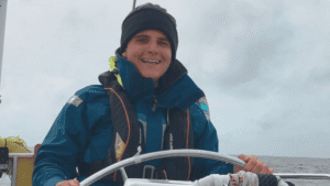 Smiling sailor steering boat on cloudy sea