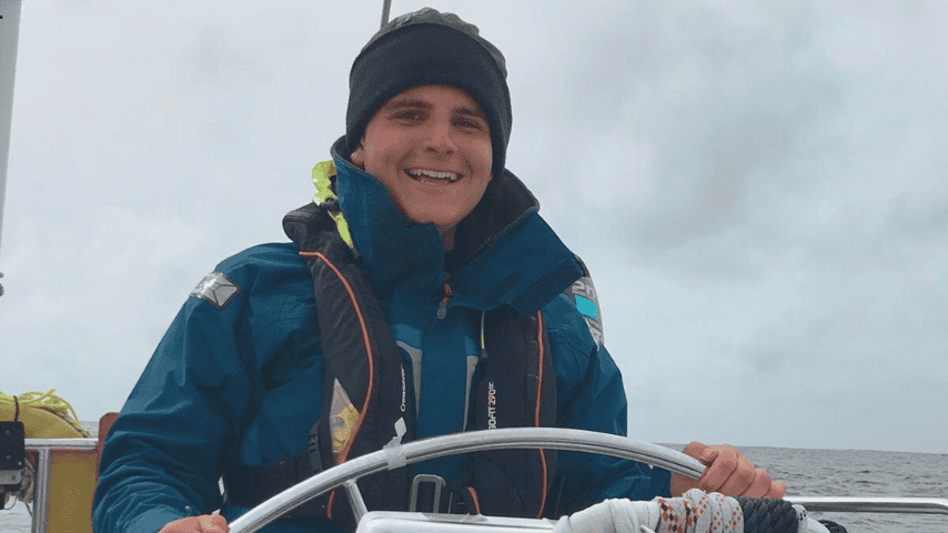 Smiling sailor steering boat on cloudy sea